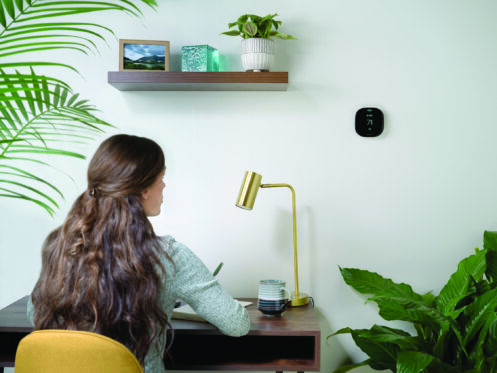 Young woman checking the thermostat while she works from home.